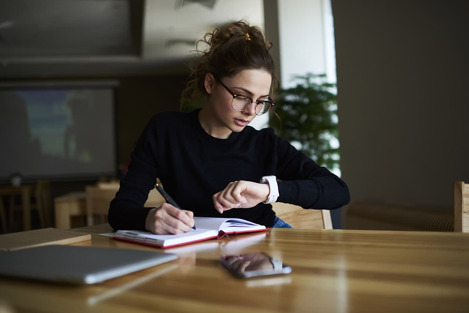 ejecutiva joven en sala de juntas revisa la hora en su reloj